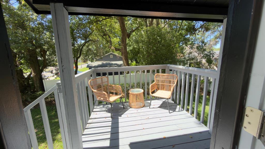 A small, elevated wooden deck features two wicker chairs and a matching side table — 1922 HILLCREST STREET, ORLANDO, FL