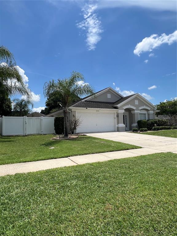 A single-story house with a white garage, a palm tree, and a white privacy fence — 3244 HERONS POINT CIRCLE, KISSIMMEE, FL