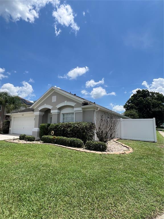 A single-story house with a white garage, beige stucco exterior, and a white privacy fence — 3244 HERONS POINT CIRCLE, KISSIMMEE, FL