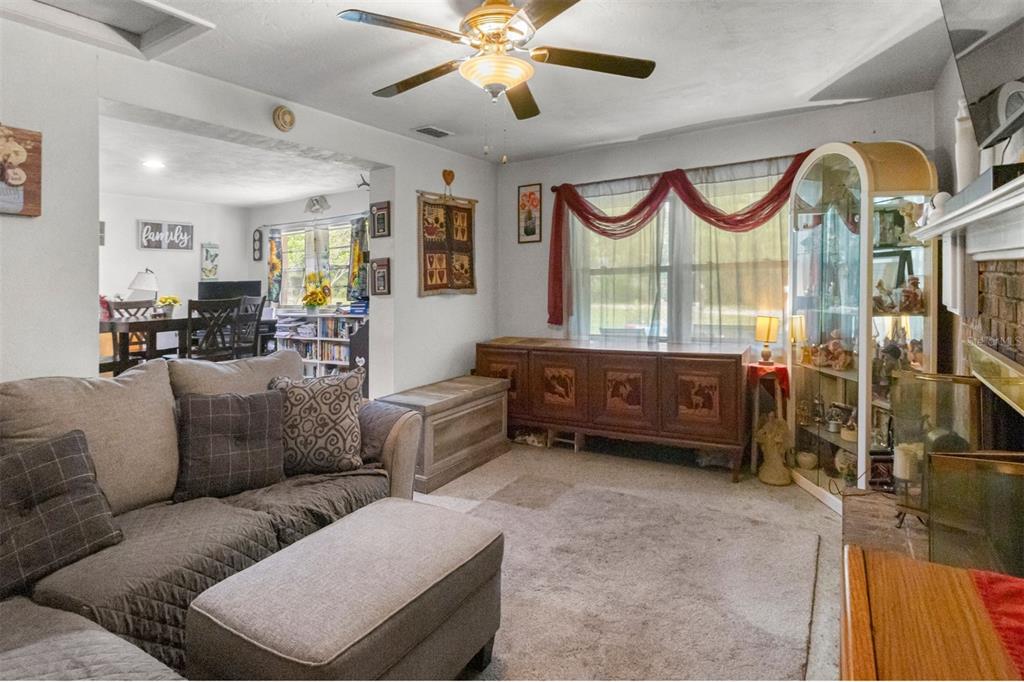 A living room features a gray sectional sofa, a ceiling fan, and a glass display cabinet — 1529 NW 143RD STREET, GAINESVILLE, FL