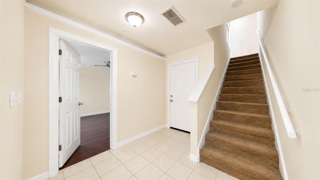 An entryway features tiled flooring, a staircase with brown carpet, and a white door — 763 SIENA PALM DRIVE, CELEBRATION, FL