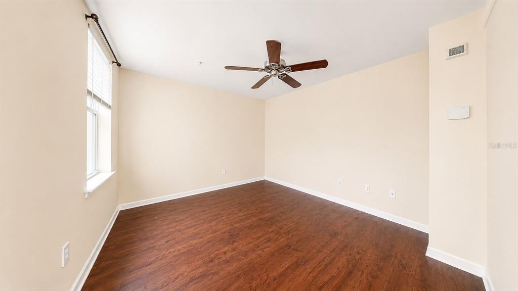 An empty room features wood-look flooring, beige walls, a ceiling fan, and a window — 763 SIENA PALM DRIVE, CELEBRATION, FL