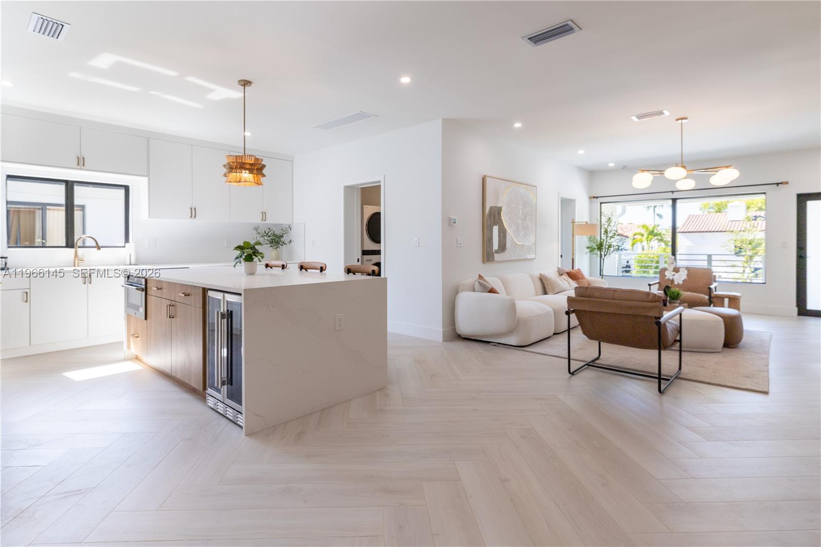 A modern open-concept kitchen and living area features white cabinetry, a stone island, and herringbone flooring — 1420 SW 17th St # 0, Miami FL 33145, MIAMI, FL