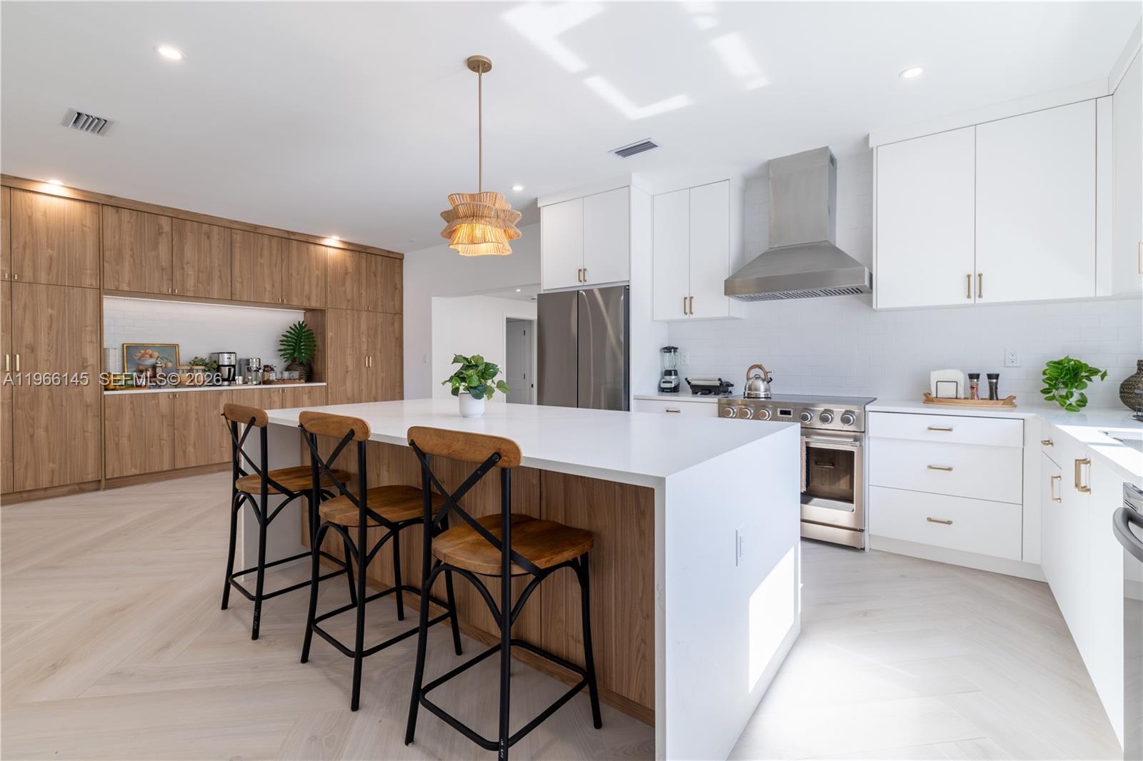 A modern kitchen features a white island with wood accents, white cabinetry, and wood-toned walls — 1420 SW 17th St # 0, Miami FL 33145, MIAMI, FL