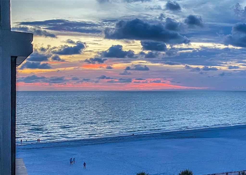 A view of a sandy beach and the ocean at sunset from a balcony — 3820 GULF BOULEVARD UNIT 608, ST PETE BEACH, FL