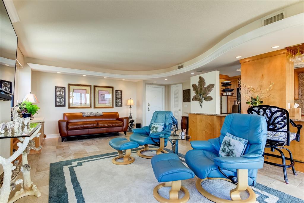 A living room features a brown leather sofa, two blue recliners, and tile flooring — 3820 GULF BOULEVARD UNIT 608, ST PETE BEACH, FL