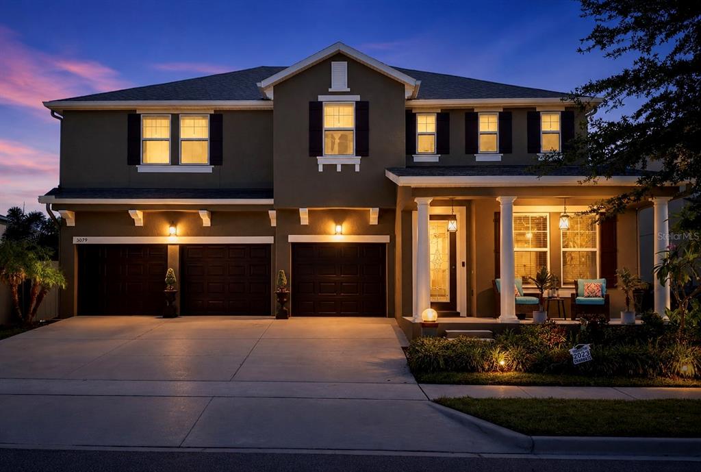 A two-story house with a three-car garage and a front porch at dusk — 5079 PALMETTO PARK DRIVE, WINTER GARDEN, FL
