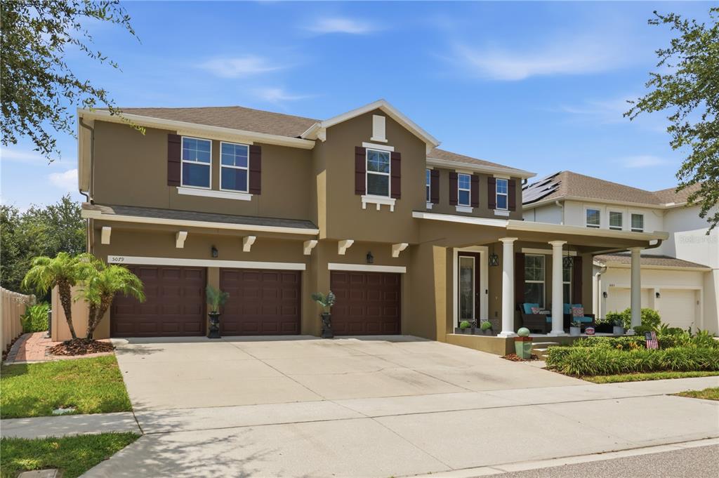 A two-story house with a three-car garage, tan stucco exterior, and a covered front porch — 5079 PALMETTO PARK DRIVE, WINTER GARDEN, FL