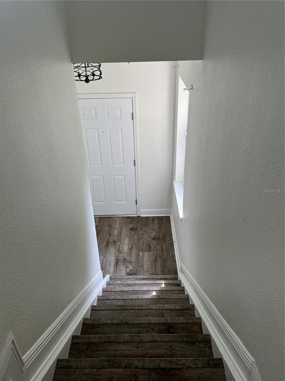 A view looking down a wooden staircase toward a white front door and entryway — 200 RIVERVIEW BEND UNIT 921, PALM COAST, FL