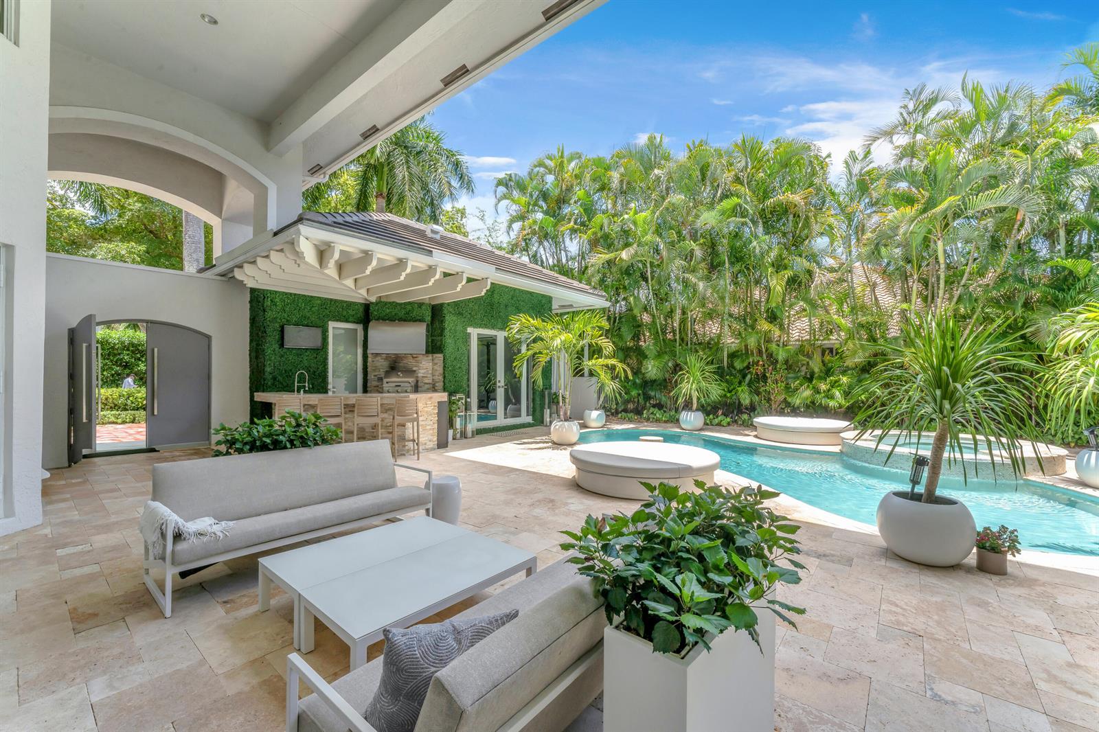 A covered patio features outdoor seating, a bar with a green wall, and a swimming pool — 3156 NW 61st Street, Boca Raton FL 33496, BOCA RATON, FL