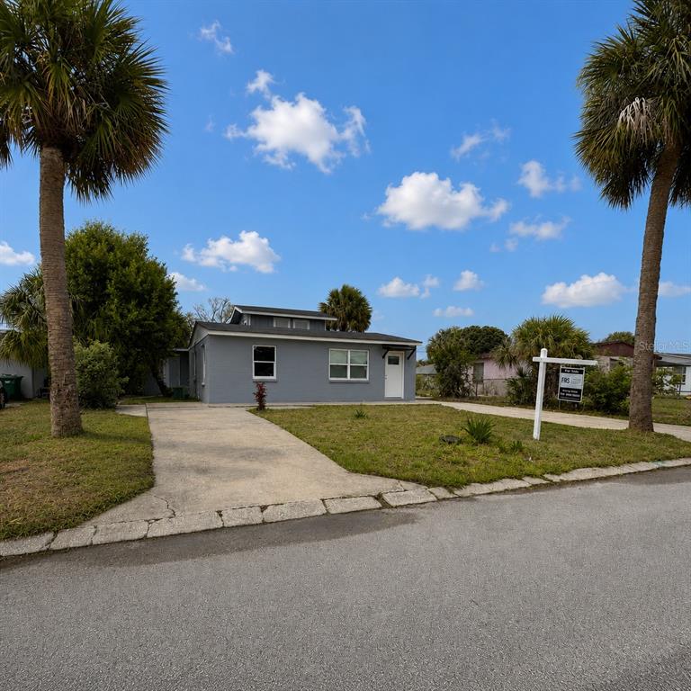 A gray, single-story house with a concrete driveway sits between two tall palm trees — 1125 GAINEY DRIVE, MELBOURNE, FL