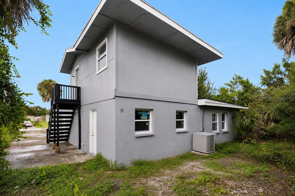 A two-story gray house with an exterior staircase and a concrete block lower level — 1125 GAINEY DRIVE, MELBOURNE, FL