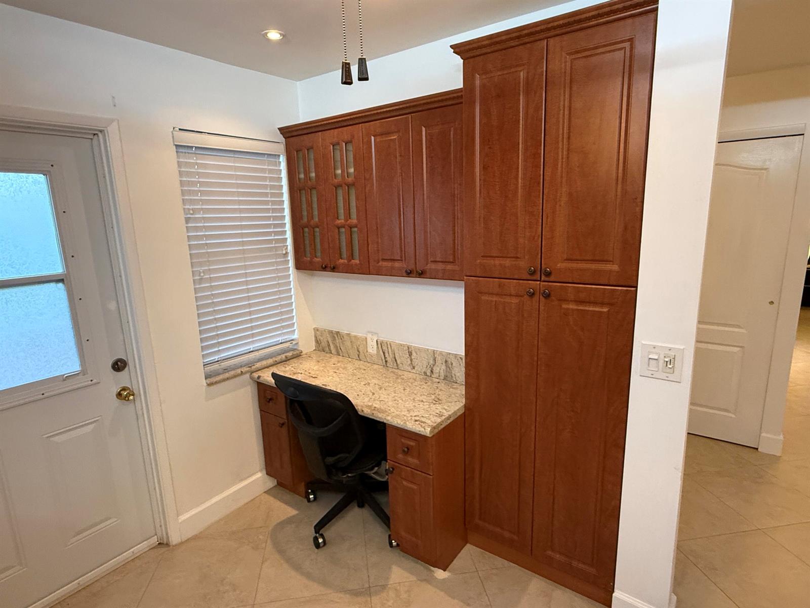 A home office nook features cherry wood cabinetry, granite countertops, and a black rolling chair — 300 NE 14th Avenue # 411, Hallandale Beach FL 33009, HALLANDALE BEACH, FL