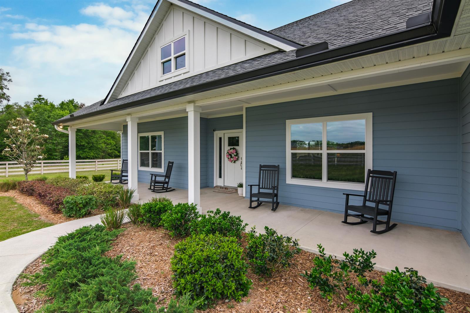 A blue-sided house features a covered front porch with four black rocking chairs — 10172 98th Path # 2, FL 32060, FL