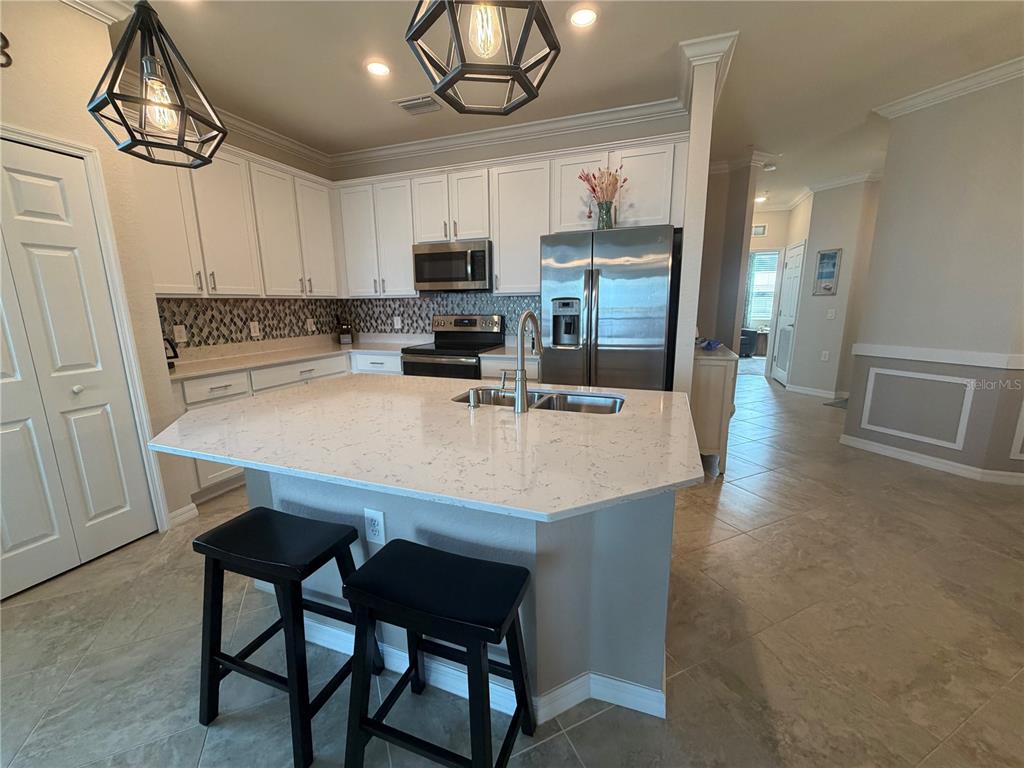 A living room with a television, ceiling fan, and sliding glass doors overlooking the water — 920 TIDEWATER SHORES LOOP UNIT 308, BRADENTON, FL