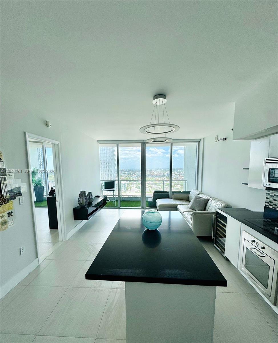 A modern open-concept kitchen and living area with floor-to-ceiling windows and a balcony — 92 SW 3rd St # 3608, Miami FL 33130, MIAMI, FL