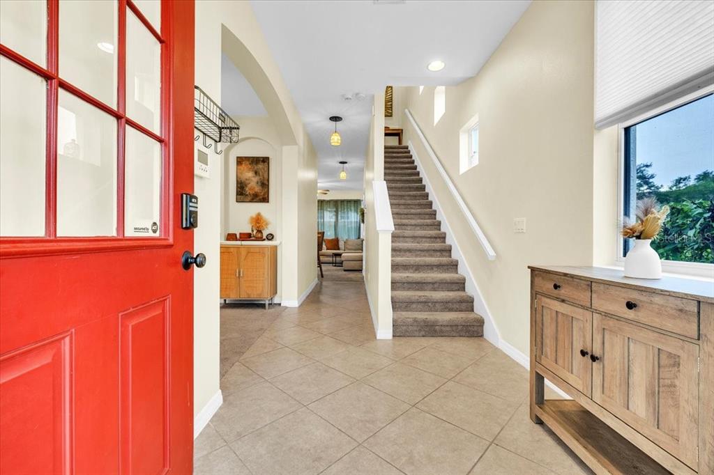 An entryway features a red front door, tiled floor, carpeted staircase, and a wooden console table — 2345 FELICITY PLACE, NORTH PORT, FL