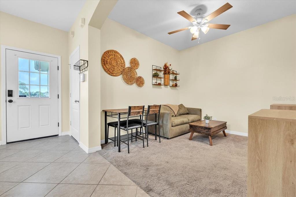 A living area features a sofa, a small dining table, wall decor, and a ceiling fan — 2345 FELICITY PLACE, NORTH PORT, FL