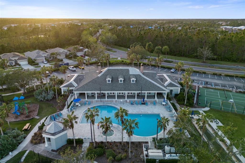 An aerial view shows a community clubhouse with a swimming pool, playground, and tennis court — 1183 JONAH DRIVE, NORTH PORT, FL