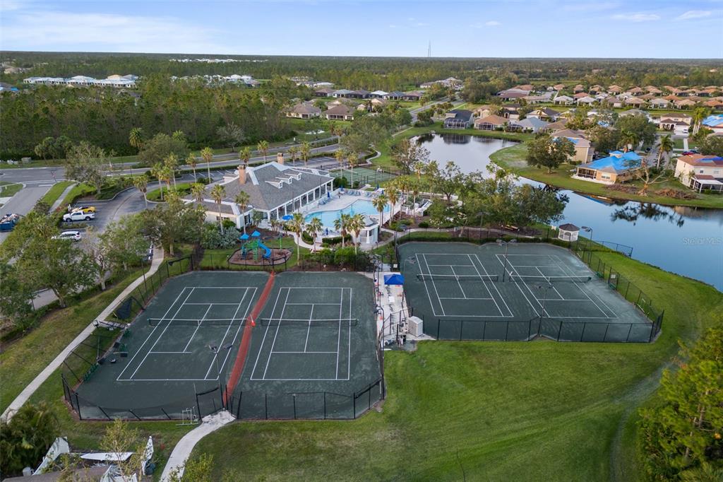 An aerial view shows a community clubhouse with a pool, playground, and four tennis courts — 1183 JONAH DRIVE, NORTH PORT, FL