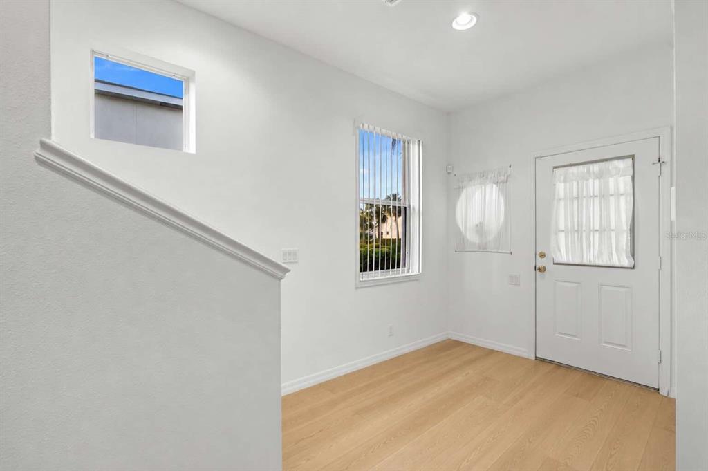 An entryway with light wood flooring, white walls, a staircase, and a white front door — 1183 JONAH DRIVE, NORTH PORT, FL