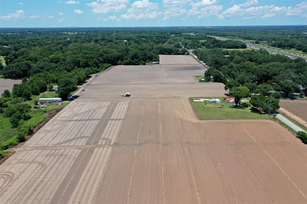 An aerial view shows a large, cleared agricultural field with a few small outbuildings — 5617 GLEN HARWELL ROAD, PLANT CITY, FL
