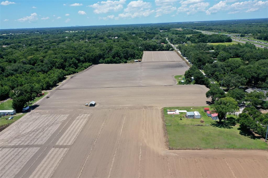An aerial view shows a large, cleared agricultural field bordered by trees and small buildings — 5617 GLEN HARWELL ROAD, PLANT CITY, FL