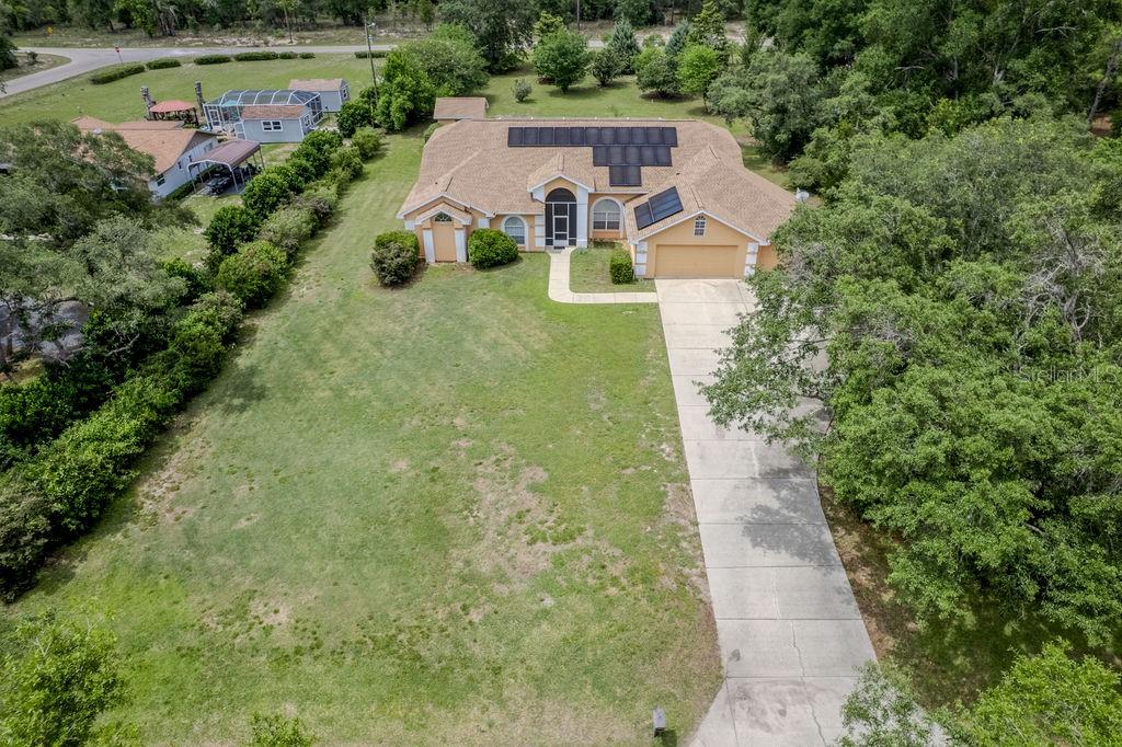 An aerial view shows a single-story house with a tan exterior, solar panels, and driveway — 20811 SW 81ST LOOP, DUNNELLON, FL