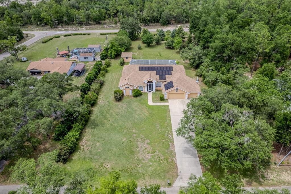 An aerial view shows a single-story house with a pool enclosure and solar panels — 20811 SW 81ST LOOP, DUNNELLON, FL