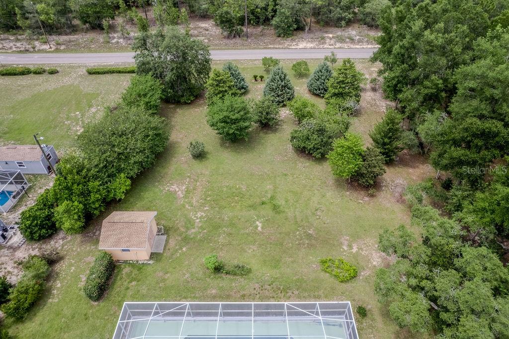 An aerial view shows a grassy backyard with a shed, trees, and a pool enclosure — 20811 SW 81ST LOOP, DUNNELLON, FL