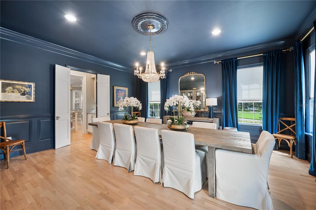 A formal dining room features dark blue walls, a crystal chandelier, and a long wooden table — 5120 LAKE IN THE WOODS BOULEVARD, LAKELAND, FL