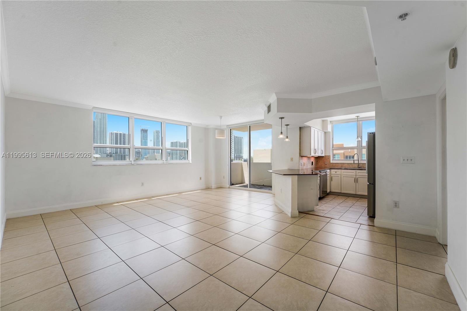 An open-concept living area features tile flooring, a kitchen with a breakfast bar, and windows — 2000 N Bayshore Dr # 702, Miami FL 33137, MIAMI, FL