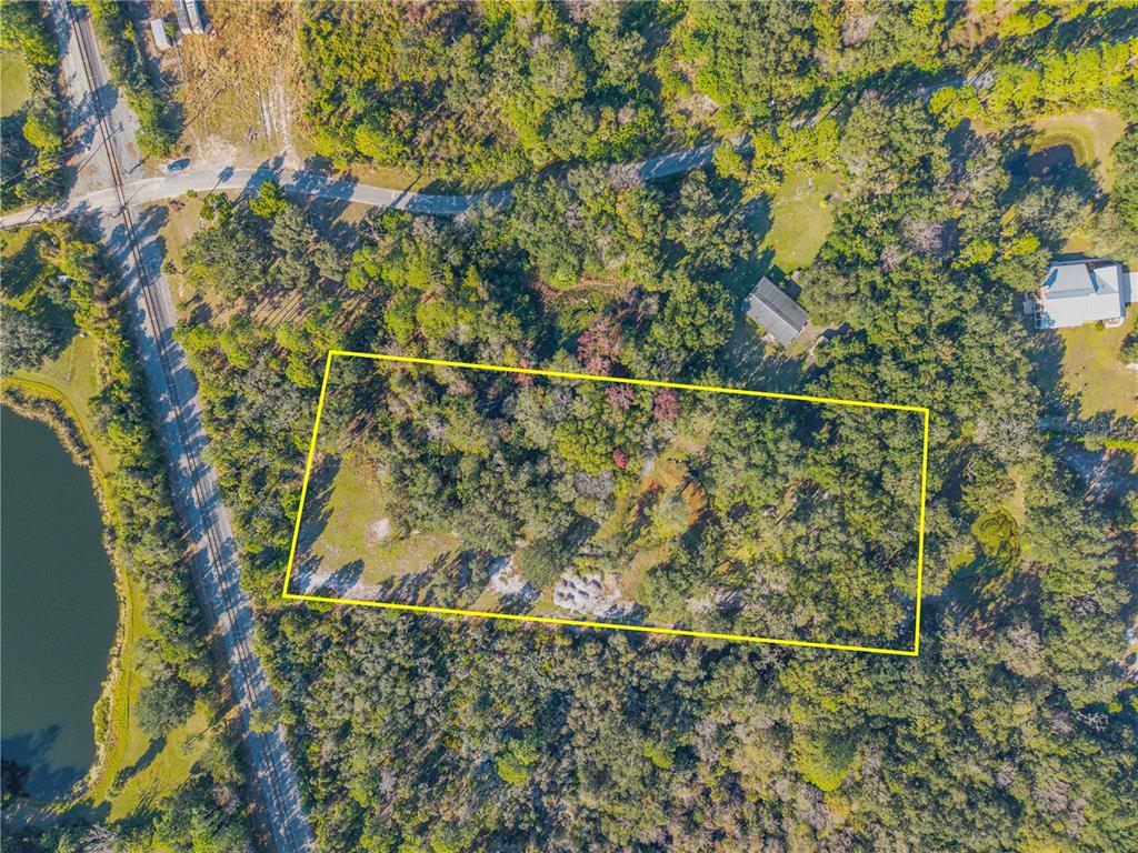 An aerial view shows a rectangular plot of land outlined in yellow amidst dense trees — 480 CLINTON CEMETERY ROAD, EDGEWATER, FL