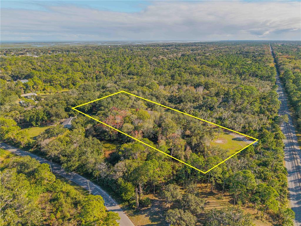 An aerial view shows a rectangular plot of land outlined in yellow amidst wooded terrain — 480 CLINTON CEMETERY ROAD, EDGEWATER, FL