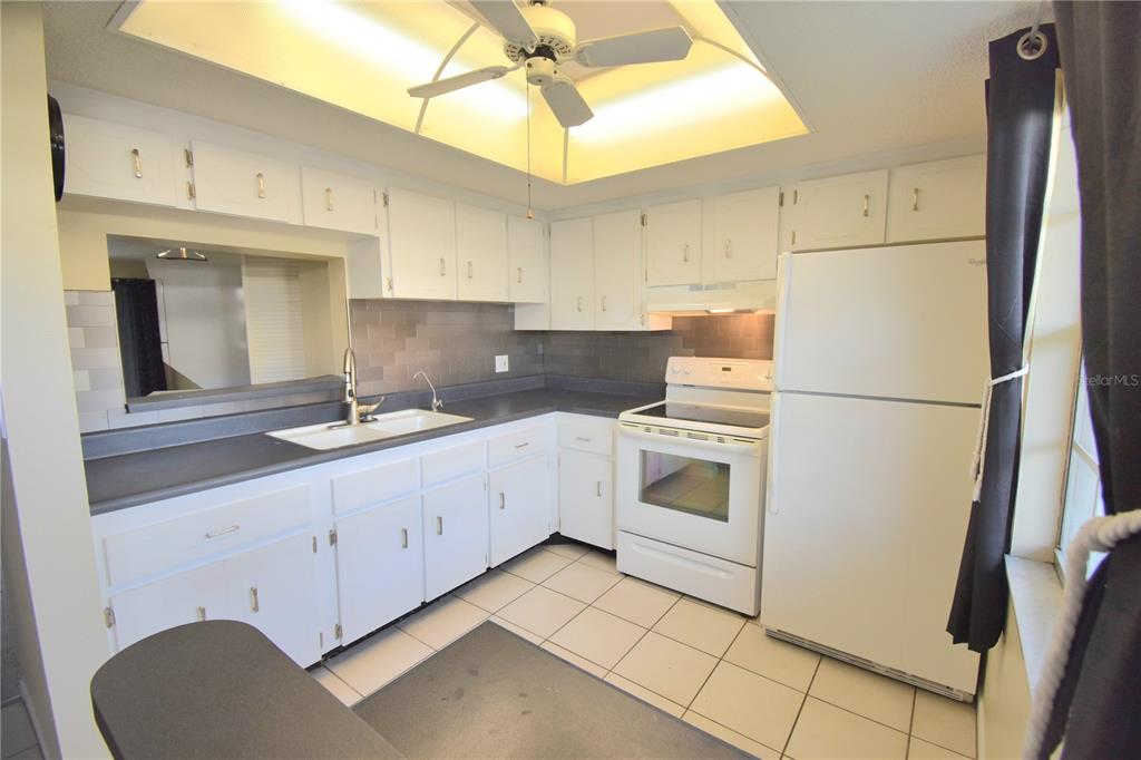 A kitchen with white cabinets, dark countertops, a white stove, and a white refrigerator — 970 VIRGINIA STREET UNIT 107, DUNEDIN, FL