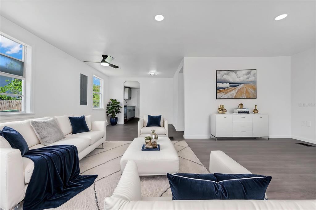 A bright living room features white furniture, navy blue accents, and gray wood-look flooring — 4311 TONY STREET, ORLANDO, FL