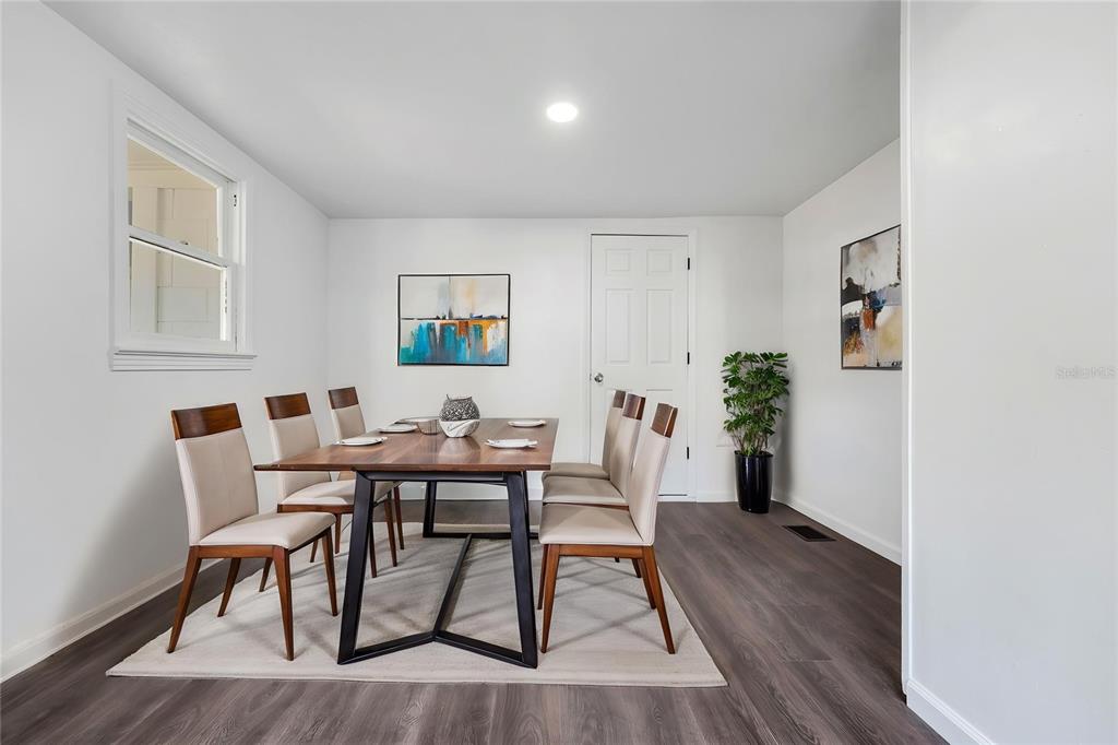 A dining room features a wooden table with six chairs on a rug over dark flooring — 4311 TONY STREET, ORLANDO, FL