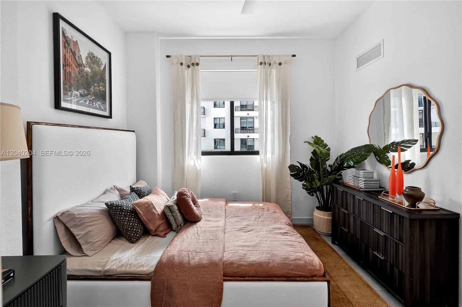 A bedroom features a bed with terracotta bedding, a dark wood dresser, and a wall mirror — 2001 Van Buren St # 1222, Hollywood FL 33020, HOLLYWOOD, FL