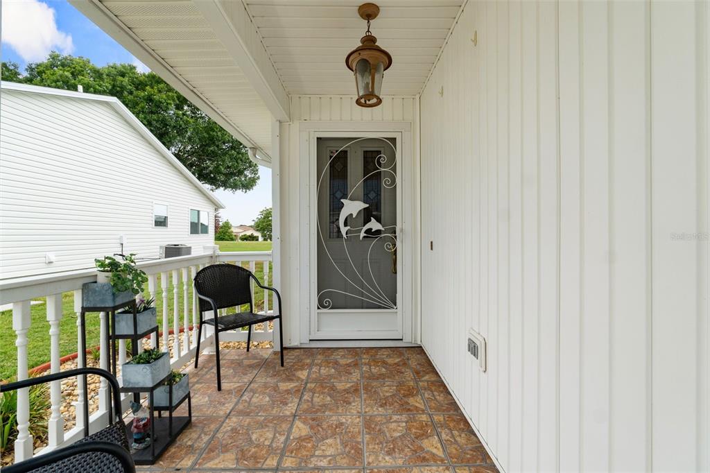 A covered porch features a tiled floor, a dolphin-themed screen door, and white railings — 3320 INNISBROOK DRIVE, LAKELAND, FL