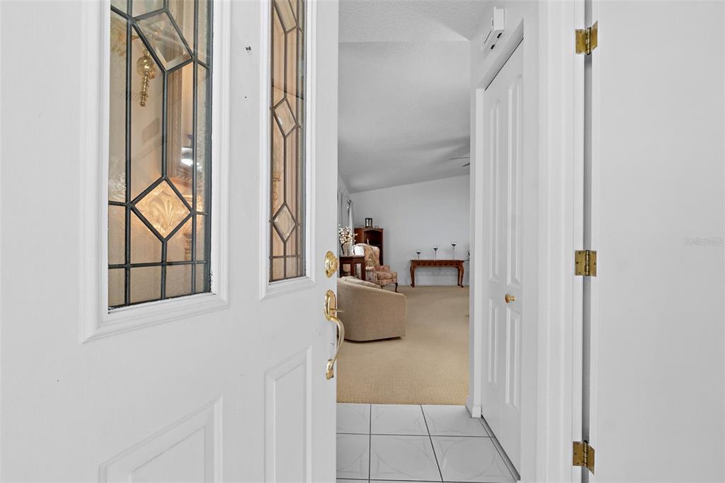 A view through an open white front door into a carpeted living room — 3320 INNISBROOK DRIVE, LAKELAND, FL