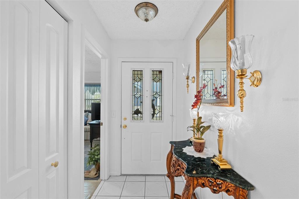 A tiled entryway features a white front door with glass inserts and a decorative console table — 3320 INNISBROOK DRIVE, LAKELAND, FL