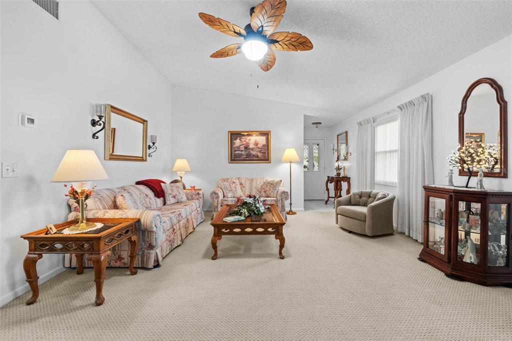 A living room features floral sofas, a coffee table, a ceiling fan, and a curio cabinet — 3320 INNISBROOK DRIVE, LAKELAND, FL