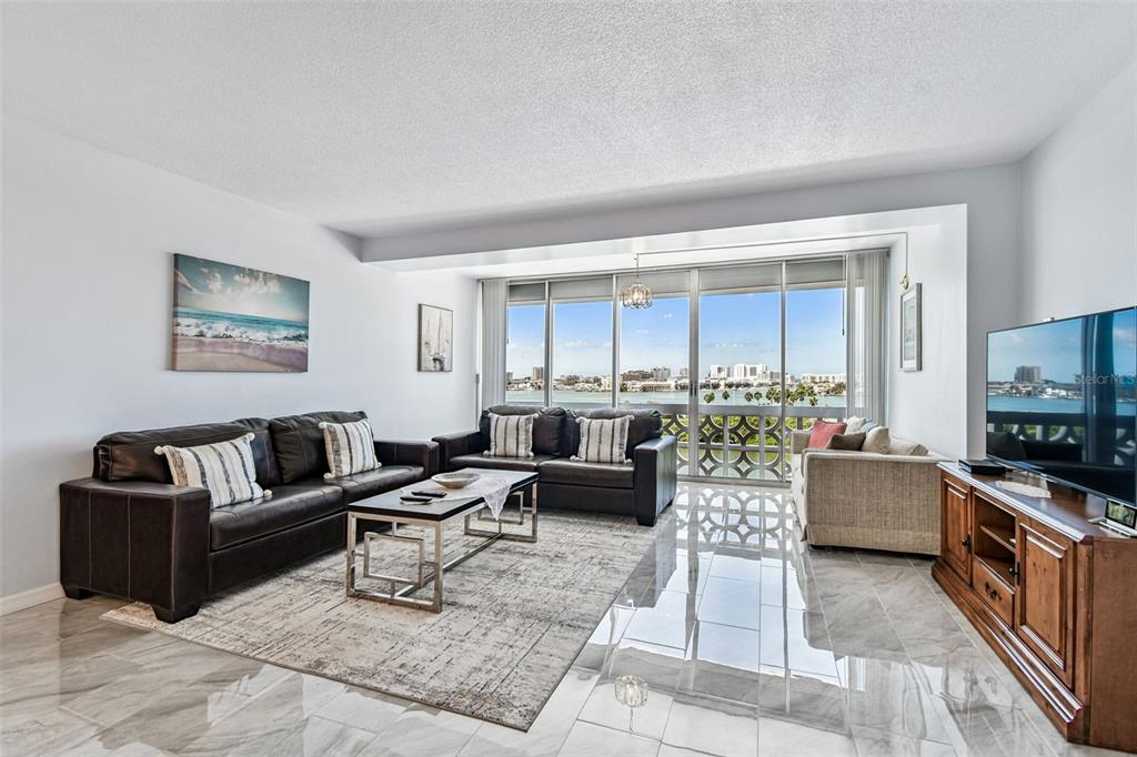 A living room features dark leather sofas, a patterned area rug, and floor-to-ceiling windows — 31 ISLAND WAY UNIT 609, CLEARWATER BEACH, FL