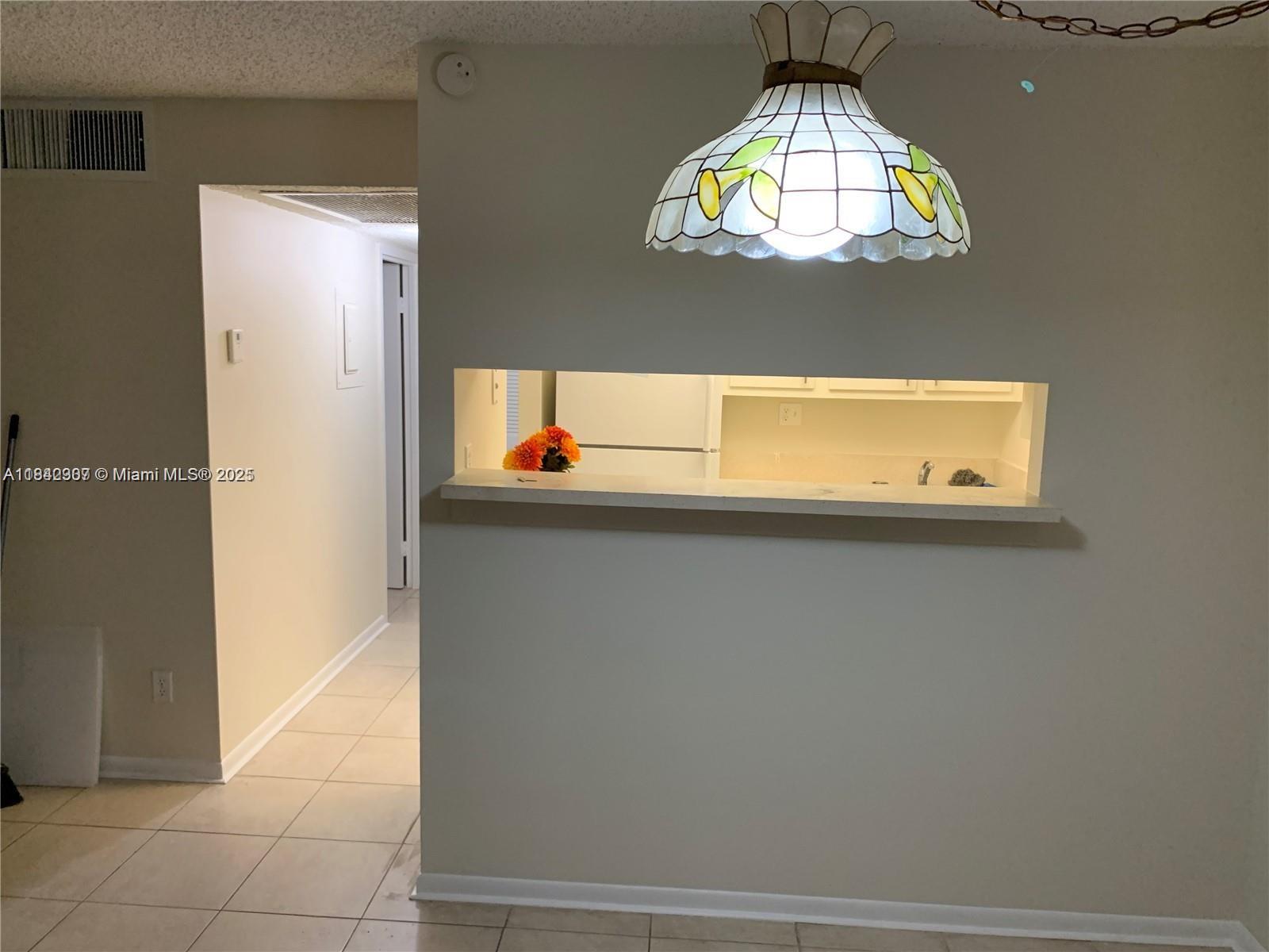 A kitchen pass-through window with a counter sits beside a hallway and a pendant light — 5831 Washington St # 45, Hollywood FL 33023, HOLLYWOOD, FL