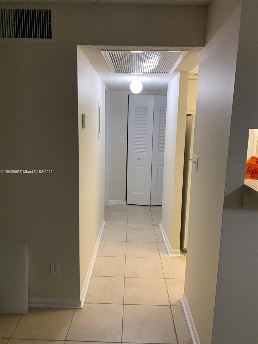 A tiled hallway leads to a white louvered closet door under a ceiling vent — 5831 Washington St # 45, Hollywood FL 33023, HOLLYWOOD, FL