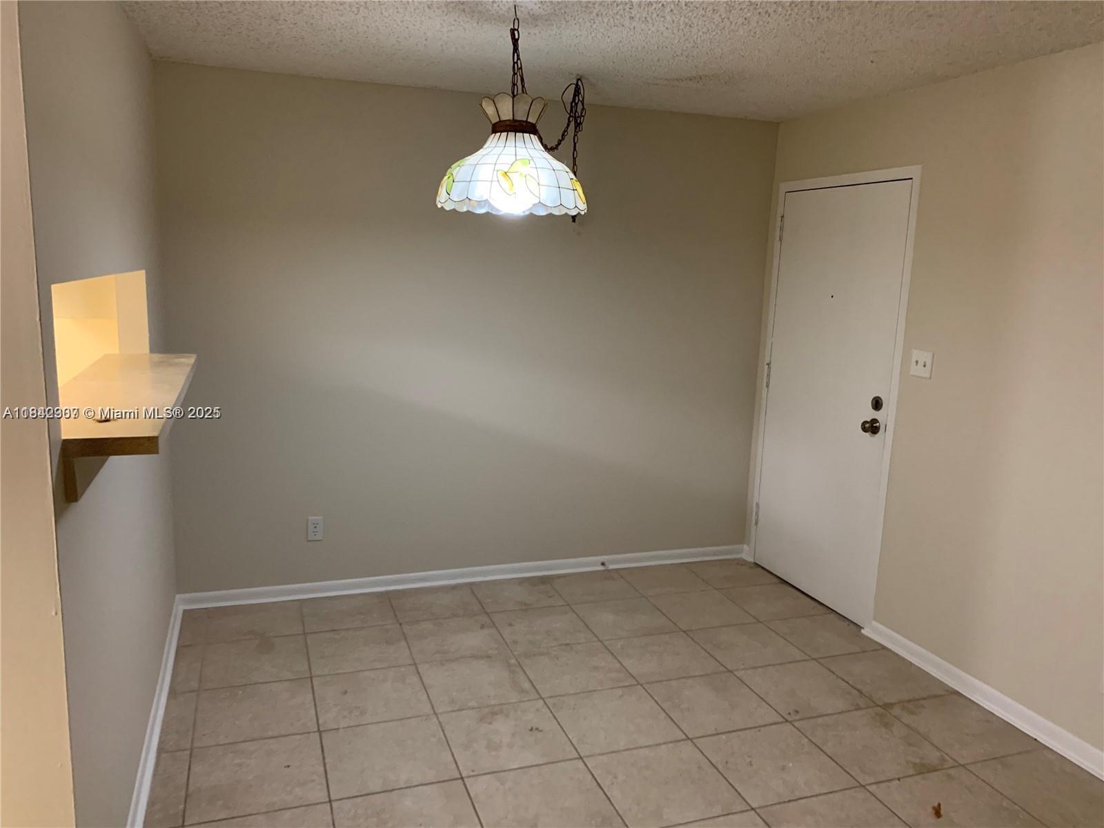 A dining area features beige walls, tiled flooring, a white door, and a hanging lamp — 5831 Washington St # 45, Hollywood FL 33023, HOLLYWOOD, FL