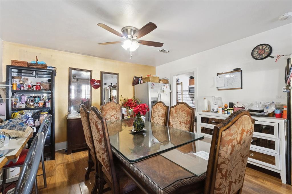 A dining room features a glass-topped table with upholstered chairs, wood flooring, and a ceiling fan — 310 E MAGNOLIA STREET, KISSIMMEE, FL