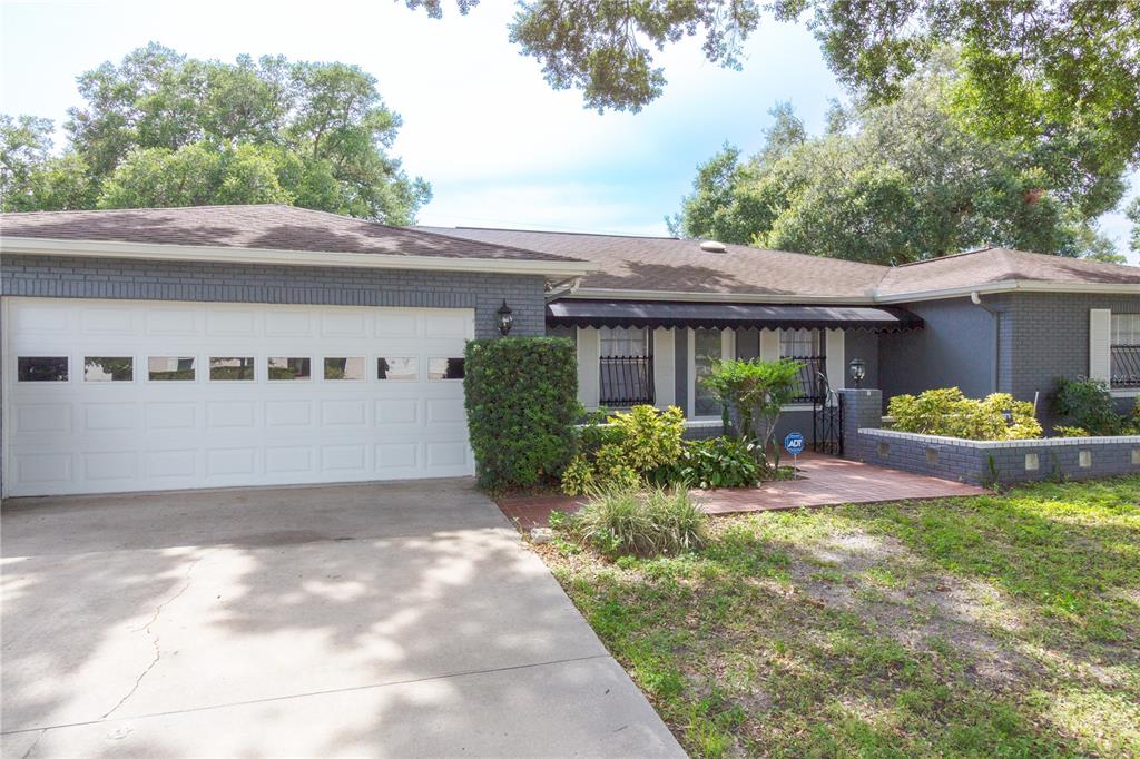 A single-story house with a gray brick exterior, a white garage door, and a front patio — 11016 SAGINAW DRIVE, TAMPA, FL