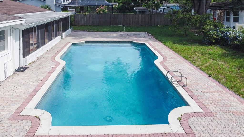 An aerial view of a rectangular swimming pool surrounded by a brick paver patio — 11016 SAGINAW DRIVE, TAMPA, FL