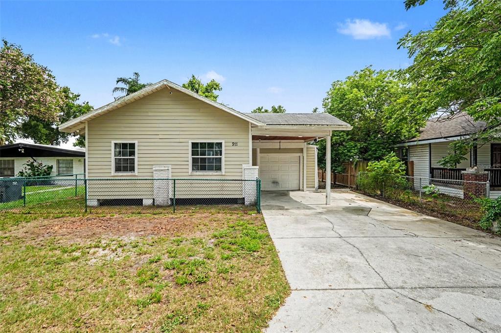 A single-story house with light siding, a front-facing carport, and a chain-link fence — 911 E 123RD AVENUE, TAMPA, FL